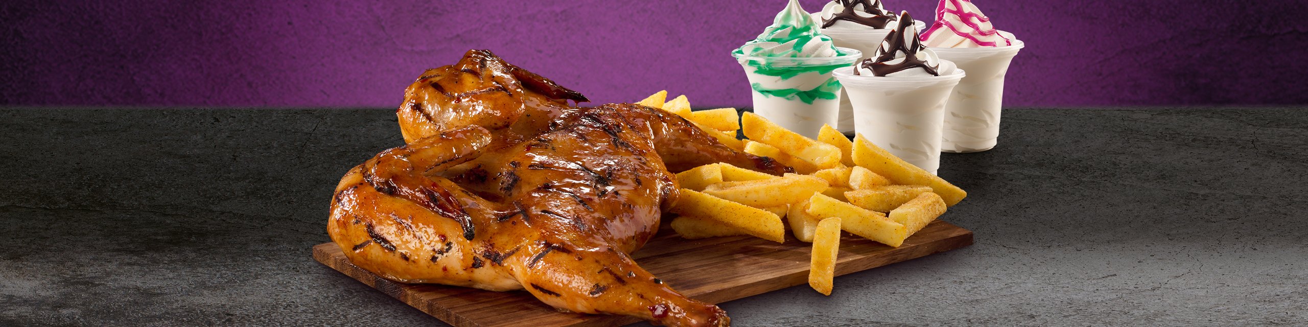Family sharing meal with a full chicken, hand-cut chips, and four cups of ice cream on a granite surface.