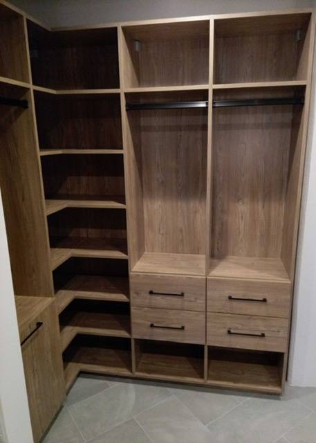 Warm Walk-In Closet A wood-finish walk-in closet offering both hanging and shelving options.