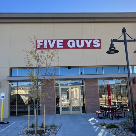 Exterior photograph of the entrance to the Five Guys restaurant at 1286 Interquest Parkway in Colorado Springs, Colorado.