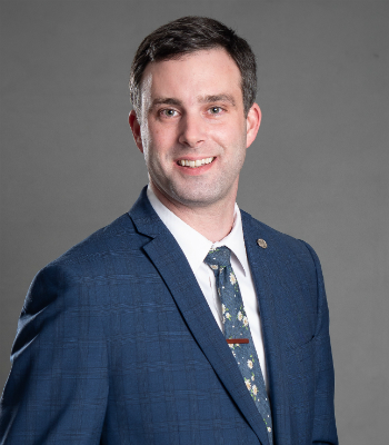 Male agent Aaron Monds in front of a grey background