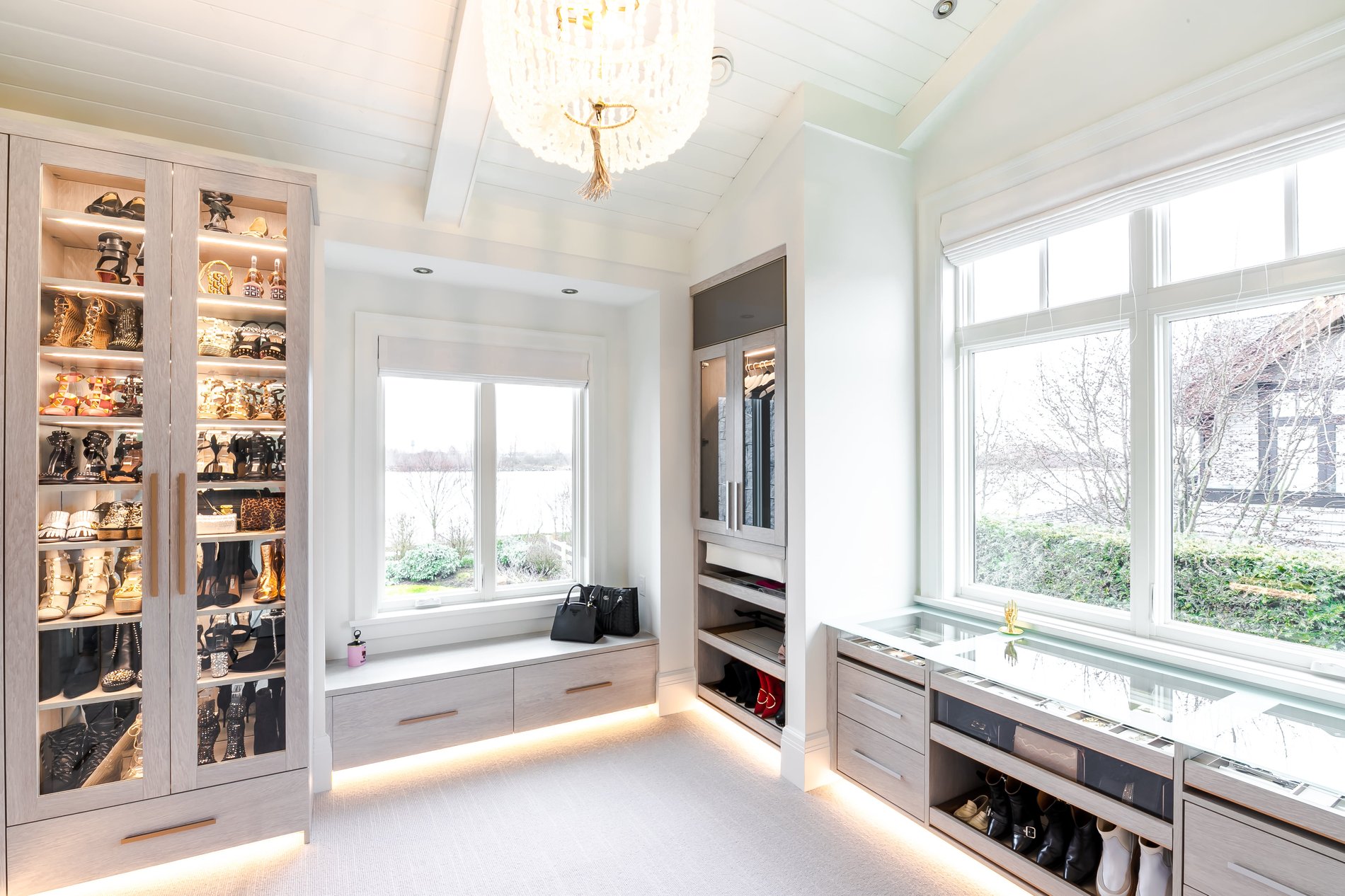 Walk-in closet with window bench Walk in closet with built in bench seating and display cabinet for jewelry