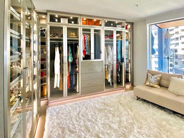 Neutral colored custom walk in closet design with lighting storage and bench by California Closets San Diego, California. Neutral colored custom walk in closet design with lighting storage and bench by California Closets San Diego, California.
