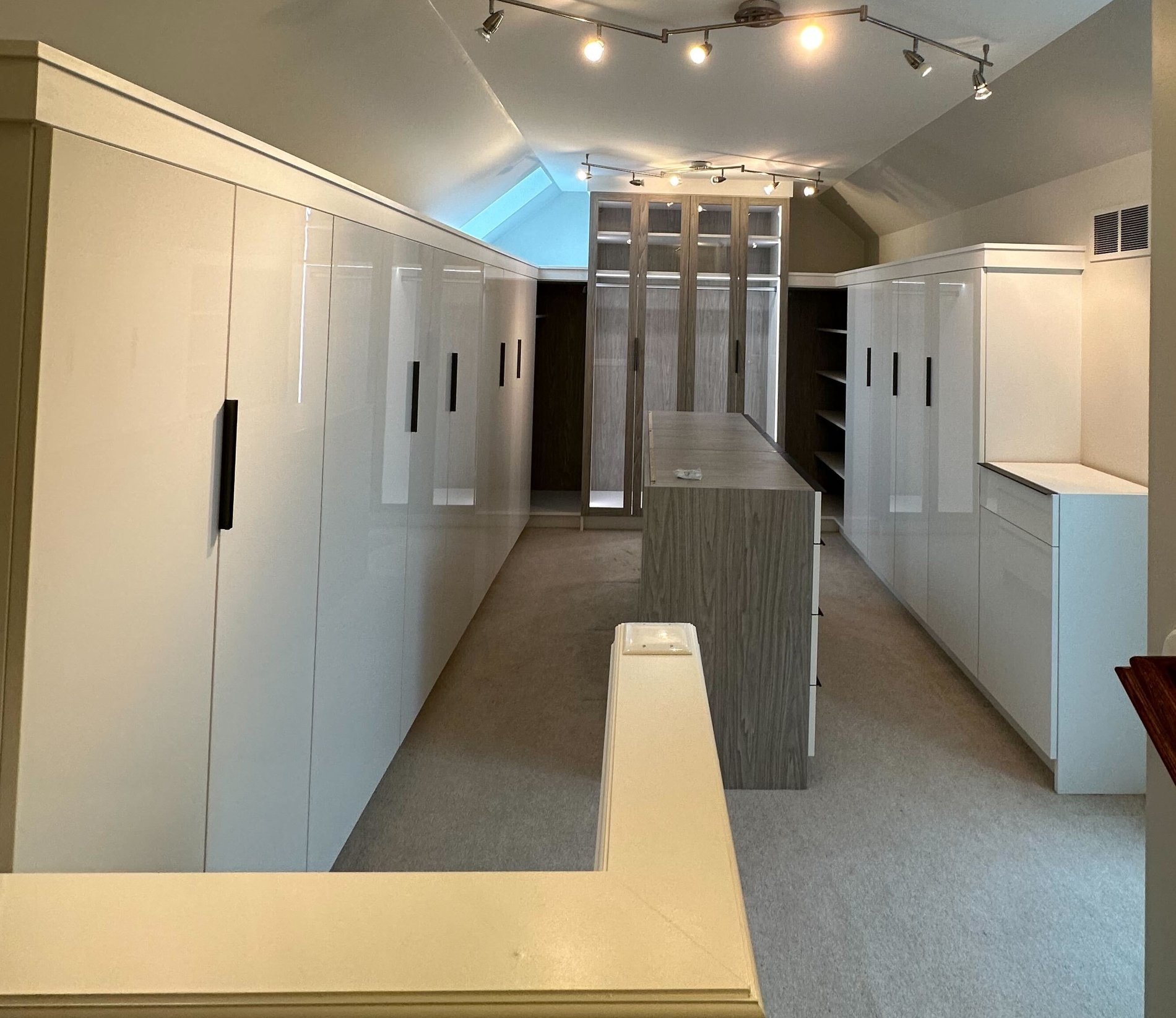 Dressing Room Walk in closet with roof line, glass doors, an island and high gloss doors