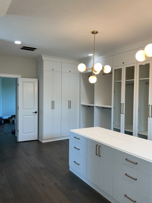 Walk In Closet with Island Custom walk in closet with island and pull out laundry hampers.