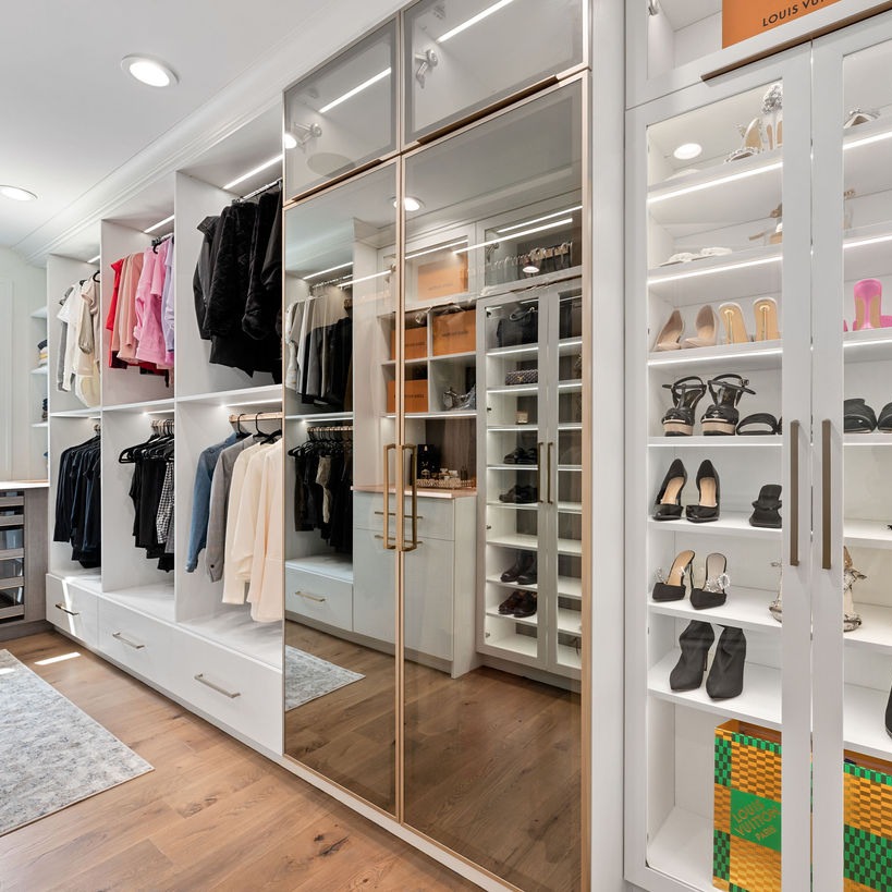 Custom Walk-in walk in closet with gold framed mirror doors, and shoe shelves