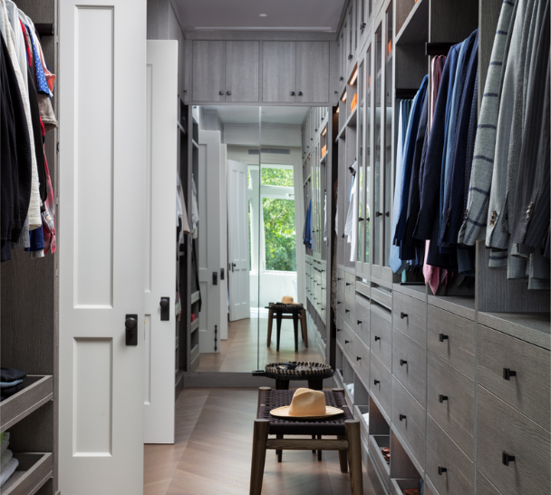 Sleek Walk-in Closet Light Gray full-room walk-in closet with drawers, custom jewelry drawers, LED lighting, glass see through doors over hanging clothes, and modern black hardware Westchester NY mirrored doors