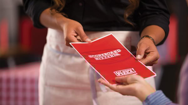 Person in restaurant receiving menu from waiter
