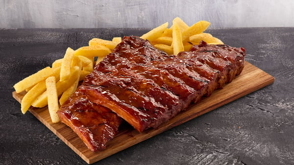 Double beef rib rack with chips on wooden board placed on a grey surface with grey background