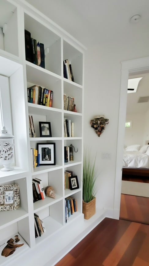 sleek open book case in hallway with window White built in book case in hallway by California Closets St. Petersburg, Florida.