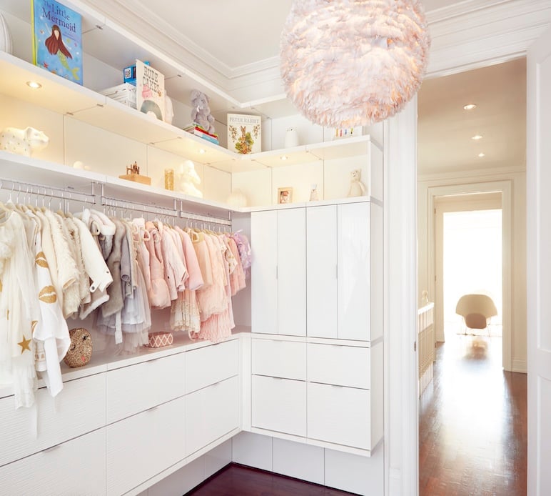 A Closet Made for Little Ones Walk-in closet with custom closet organization, built-in drawers, hanging storage, floating shelves and integrated lighting for a child’s wardrobe.