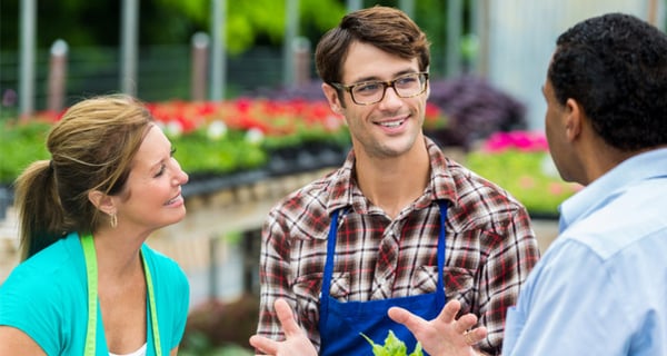 A man working at a garden nursery talking to coworkers