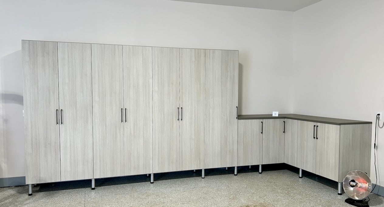 Custom Garage Organization System Custom garage storage featuring garage cabinets, garage organization systems, and built-in storage solutions. This organized garage design combines enclosed cabinetry and workspace areas to maximize storage and improve functionality. South Lyon, Michigan.