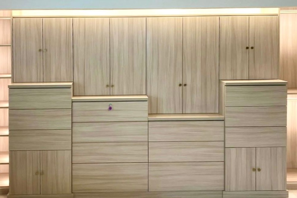 Minimalist Built-In Modern custom built-in with light wood cabinetry, concealed storage, layered drawers, and integrated lighting.