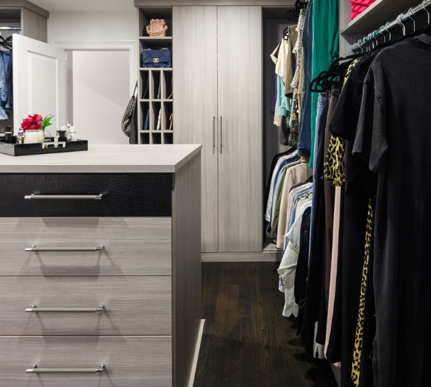 Gray Dressing Room Img 5 California Closets Westchester County NY Gray Walk-in Closet Full Room Dressing Room with Double Hanging Dedicated Shoe Wall with Lighting and a Center Island with Black Leather Jewelry Drawers