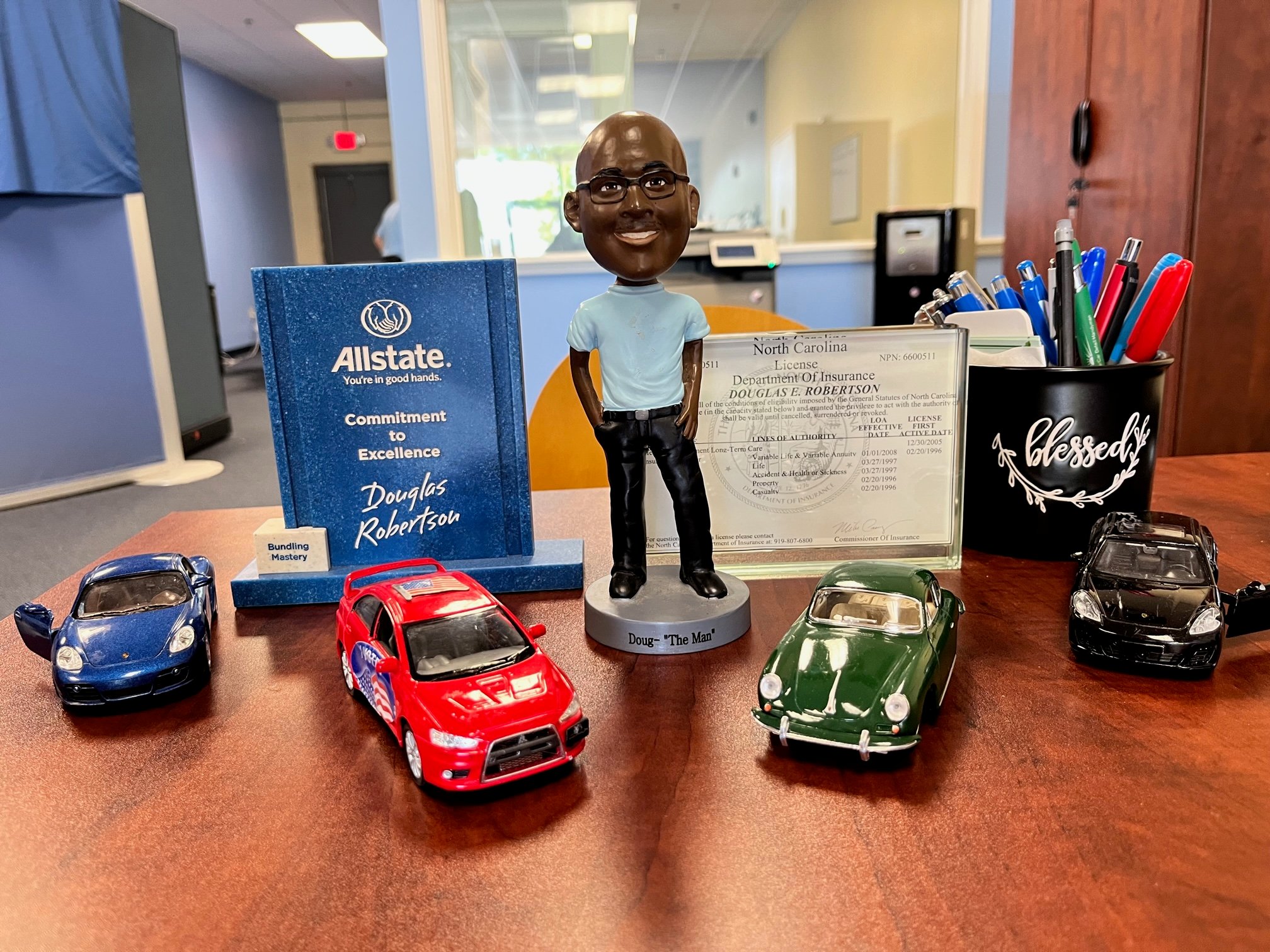 Desk with Doug Robertson's bobblehead and vintage model cars