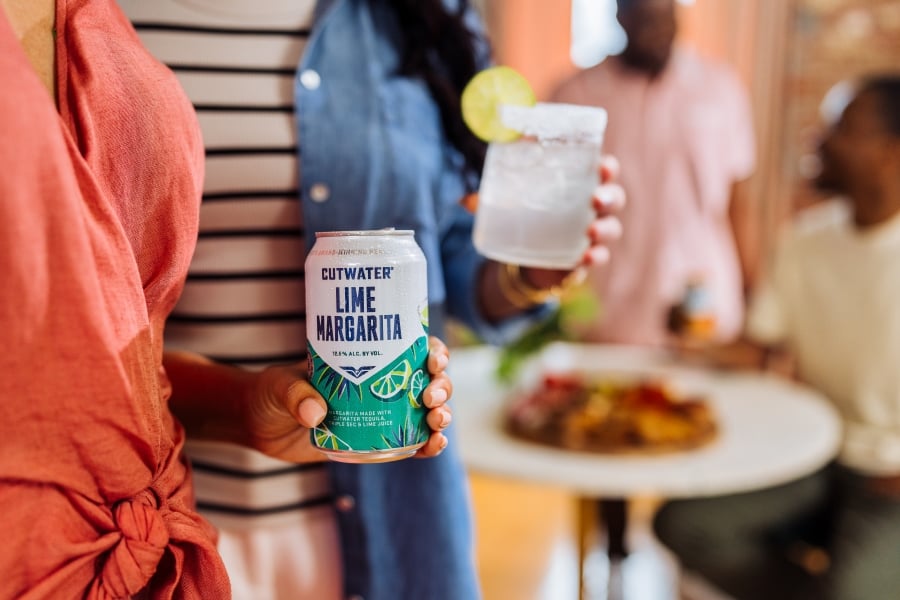 a woman holding a cutwater lime margarita can