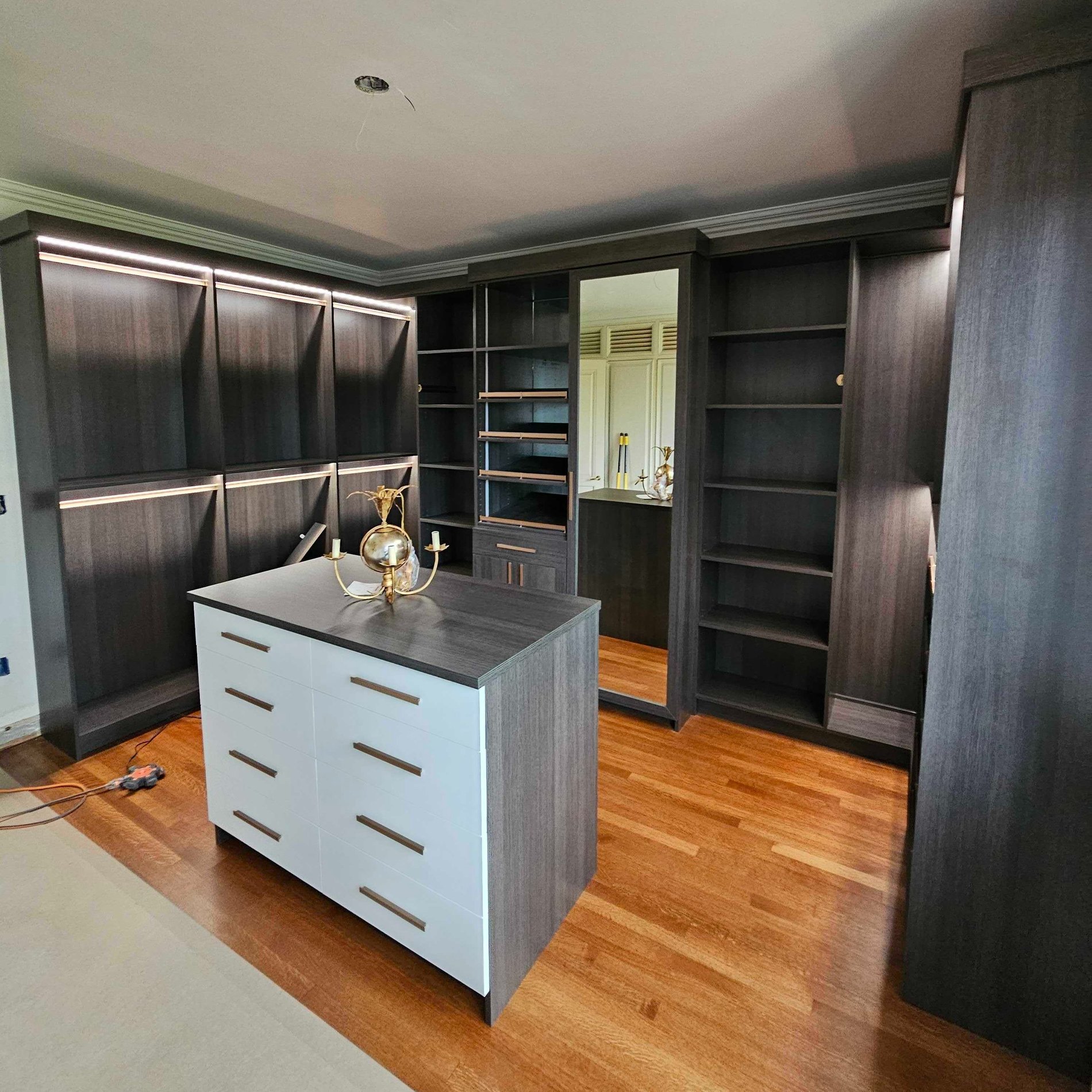 Custom Dressing Room with Integrated Lighting walk in closet with lighting, shoe space, and an island