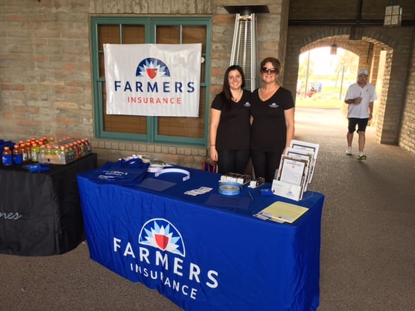 Agent Lucy with female staff member at a Farmers booth.