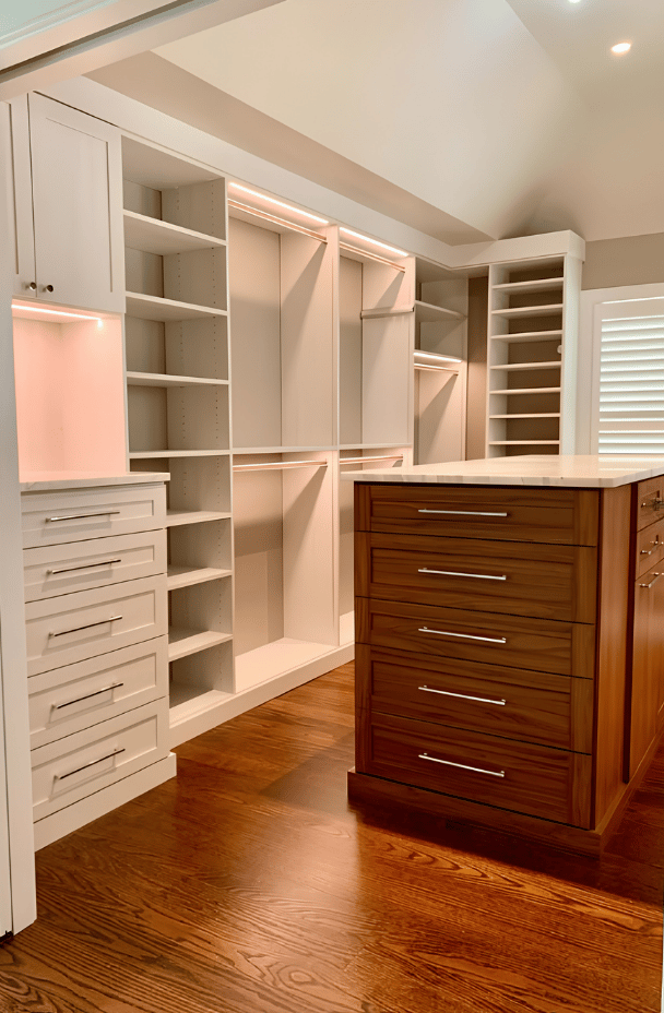 Walk-in Closet with Contrasting Finishes Off-White Walk-in closet with dark wood center island