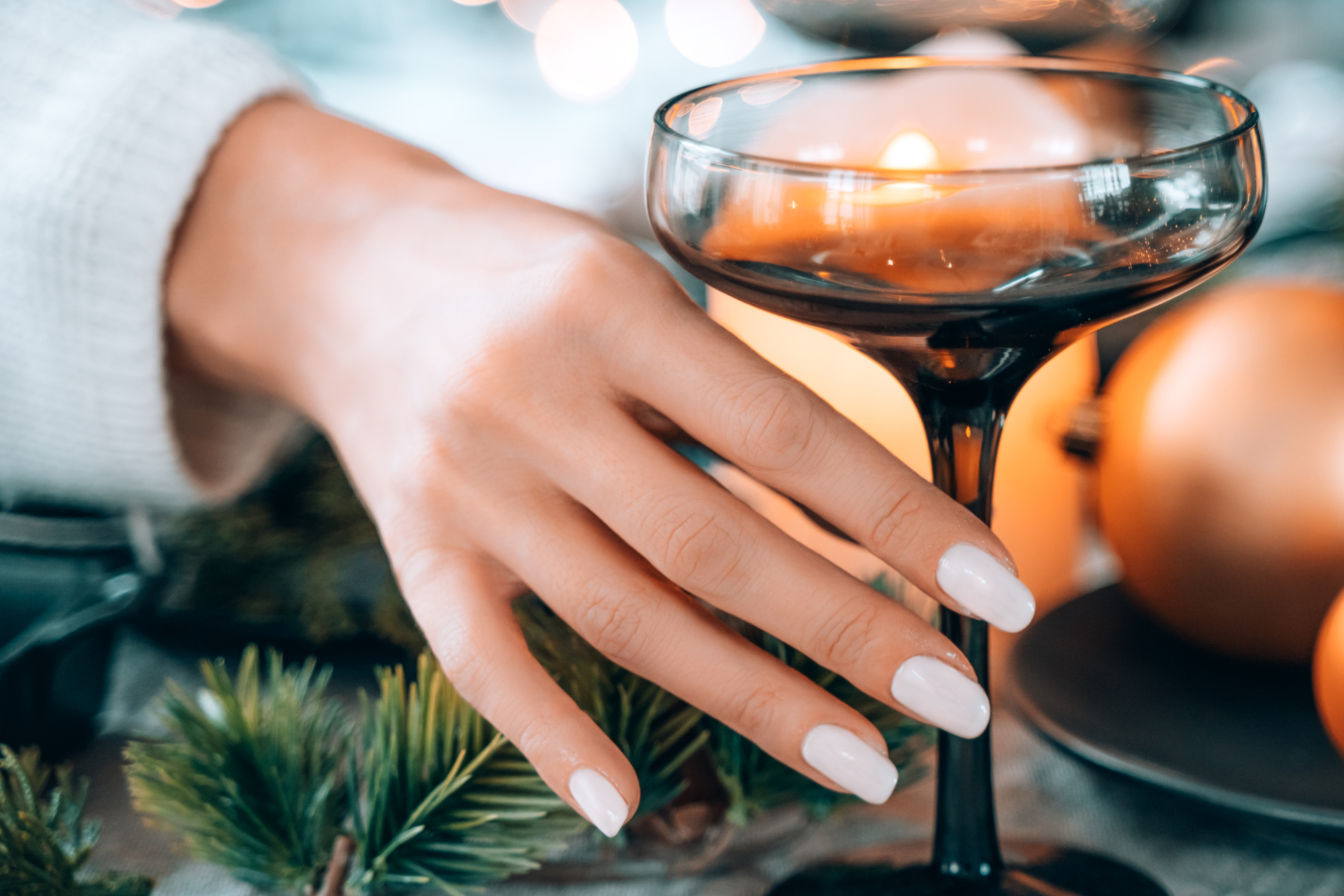 A woman showing off Farmhouse Fresh manicure, holding champagne glass
