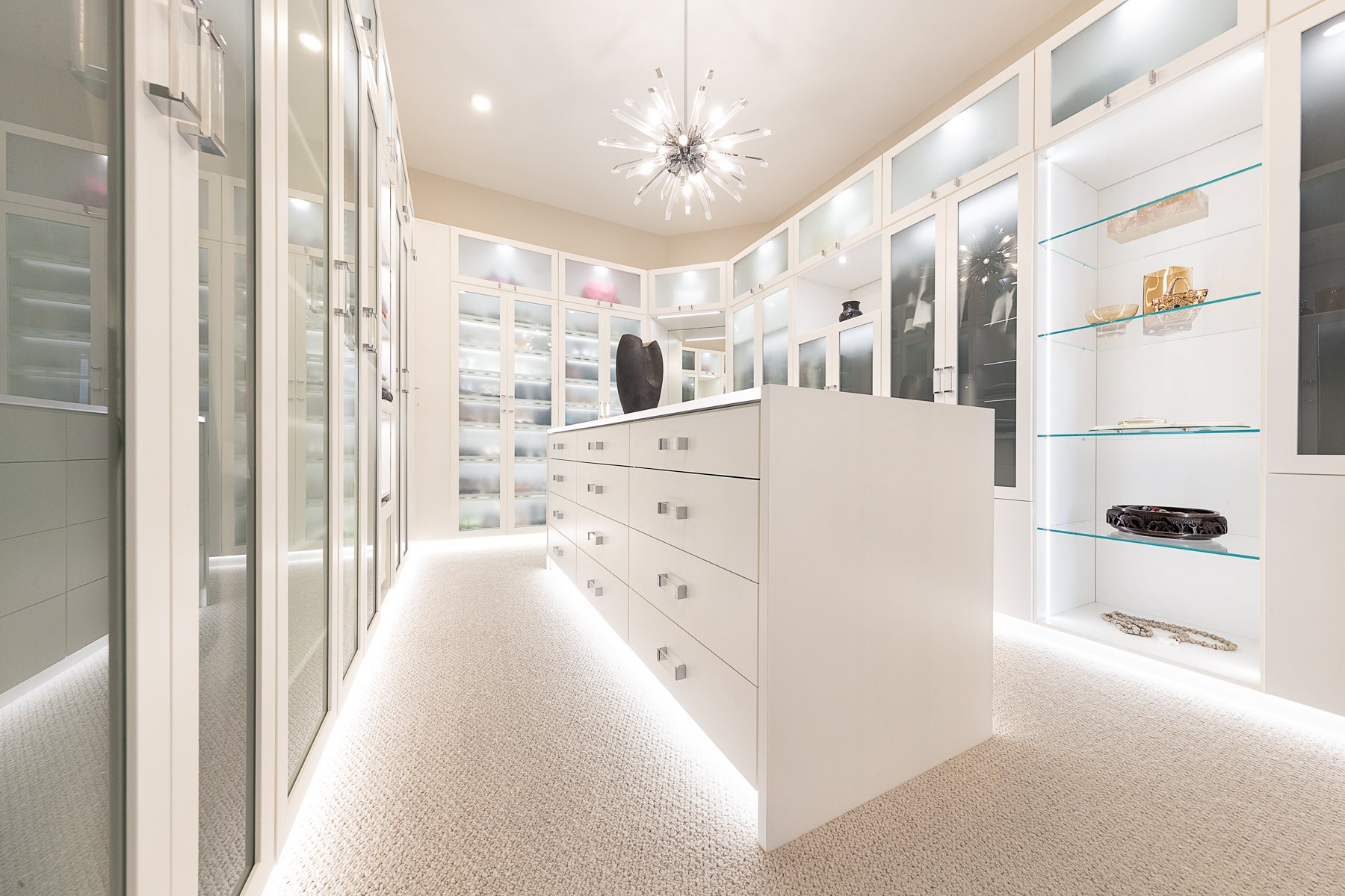 Light and Bright Floor to ceiling storage with lighting, glass doors and shelves, and a centre island.