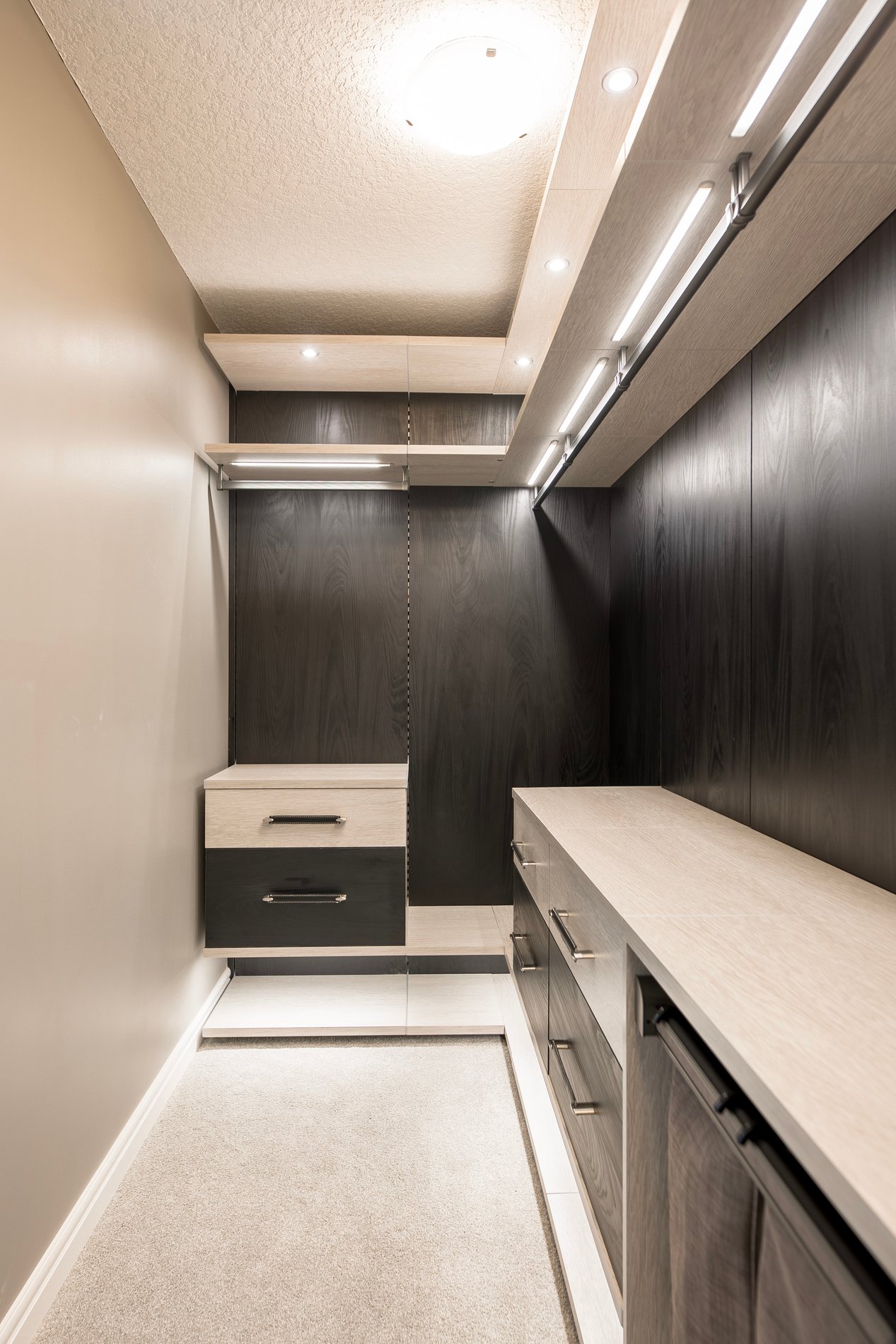 Contrasting Modern Walk-In Closet Narrow walk in closet, design in a modern style with floating shelves, contrasting colors, black backing, and lighting.
