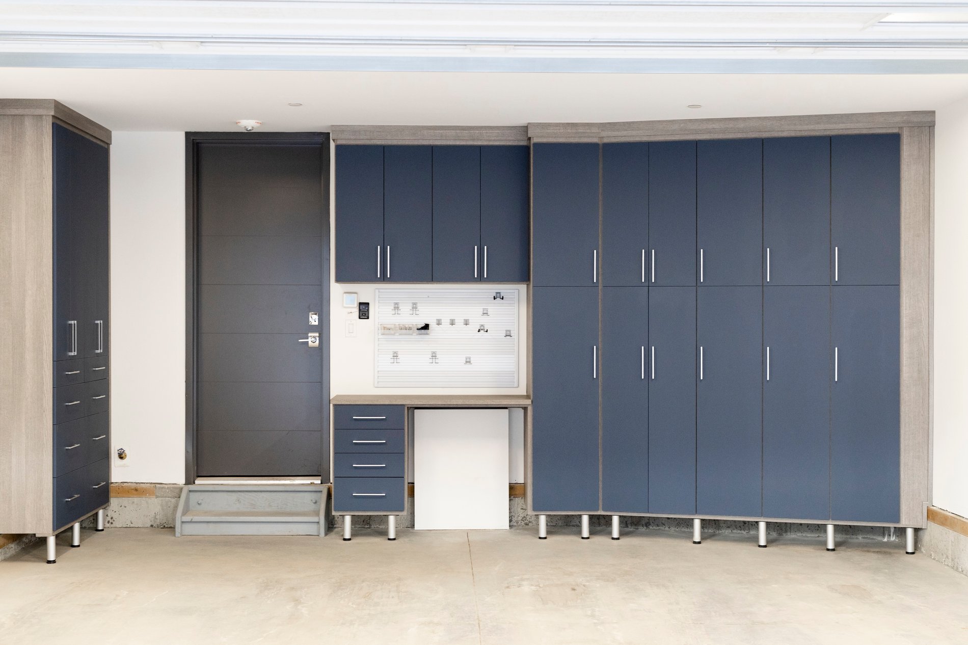 Custom Dark Blue Garage Storage Custom garage design with dark blue door fronts and gray wood grain finish.