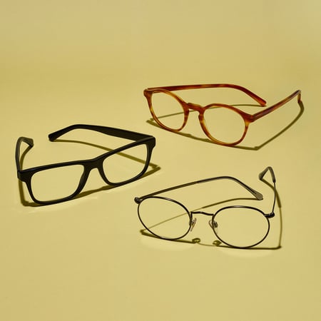 Collection of three prescription eyeglasses on a solid yellow background
