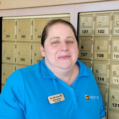 Smiling female associate standing in front of mailboxes in The UPS Store
