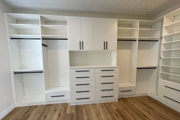 Simple and clean white custom closet cabinetry designed and built by California Closets San Diego. Modern walk-in closet with yellow accents by California Closets San Diego, California.