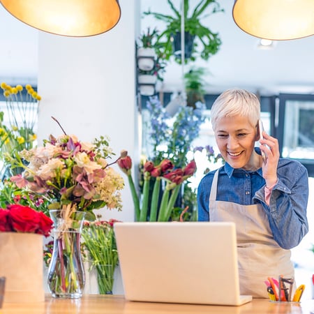 Florist using phone and computer for online banking