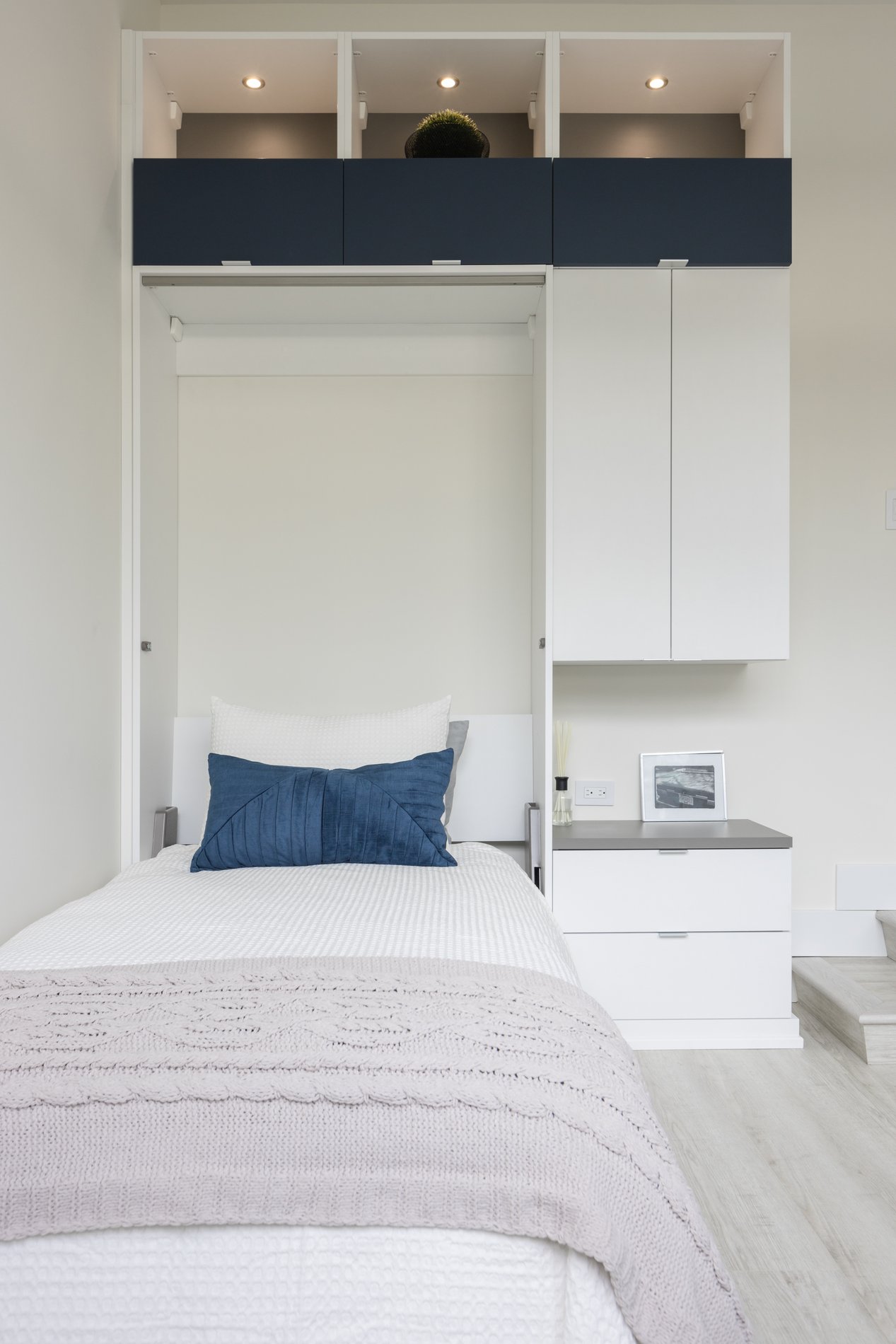 Single Murphy bed with storage and built in lighting A front on view of murphy bed pulled out, with storage to the right and top
