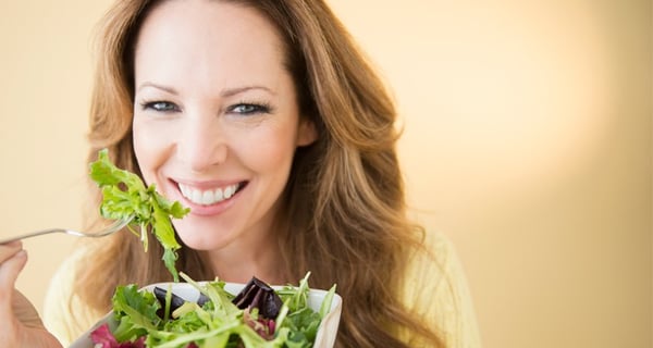 Smiling woman holding bowl of salad