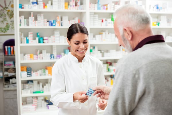 Pharmacist smiling as she hands a customer some medicine