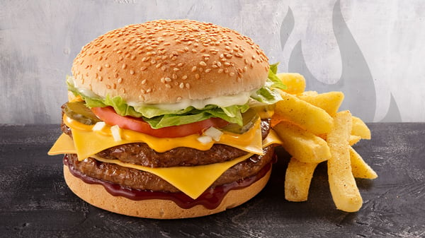 The King Steer® burger with chips on a grey surface with a grey background.