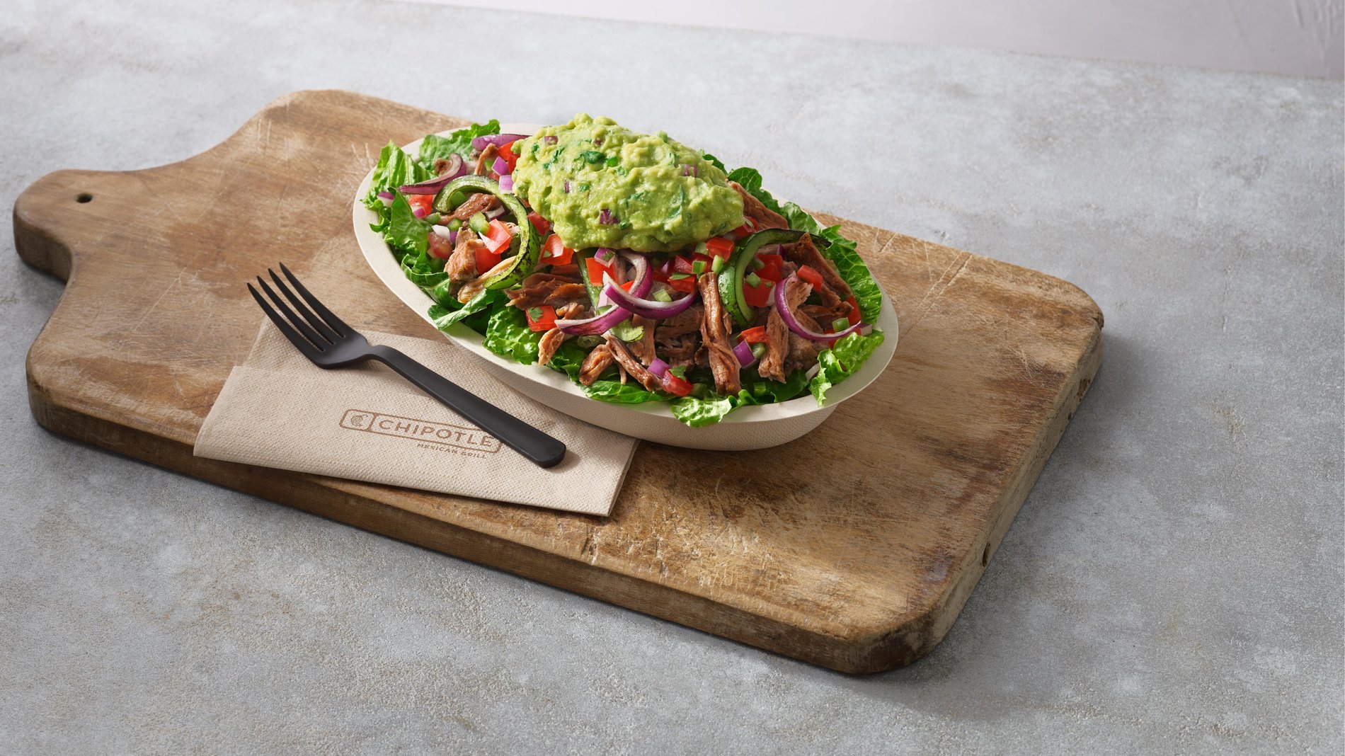Whole30 salad bowl on a wooden cutting board with a fork and napkin