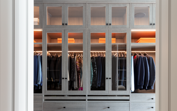 Modern Walk-in Closet Light Gray full-room walk-in closet with drawers, custom jewelry drawers, LED lighting, glass see through doors over hanging clothes, and modern black hardware Westchester NY