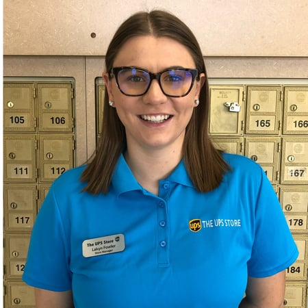 Smiling female associate standing in front of mailboxes in The UPS Store