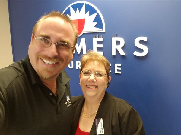 Agent and woman photo standing in front of Farmers® logo