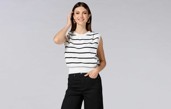 Woman is wearing a short sleeve black and white striped sweater with black pants.