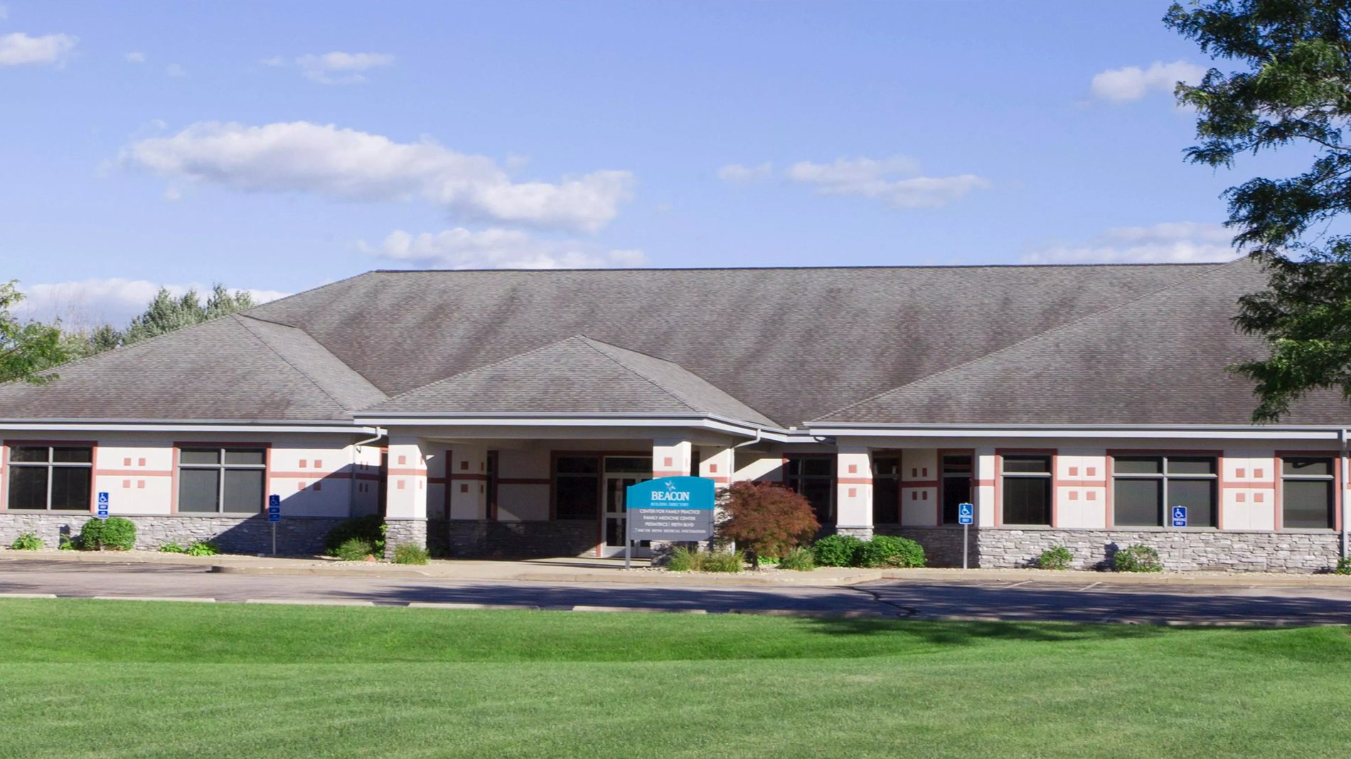 The entrance of Beacon Medical Group Goshen Family Medicine Center, a white building with red accents