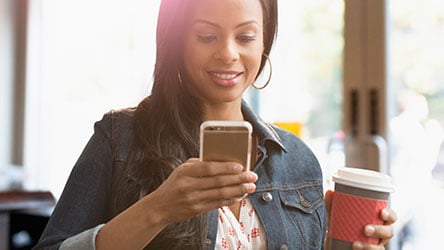 Lady with her cell phone and a cup of coffee.