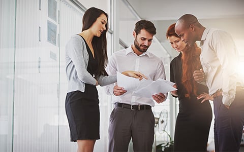 Group of work colleagues standing and reviewing paperwork