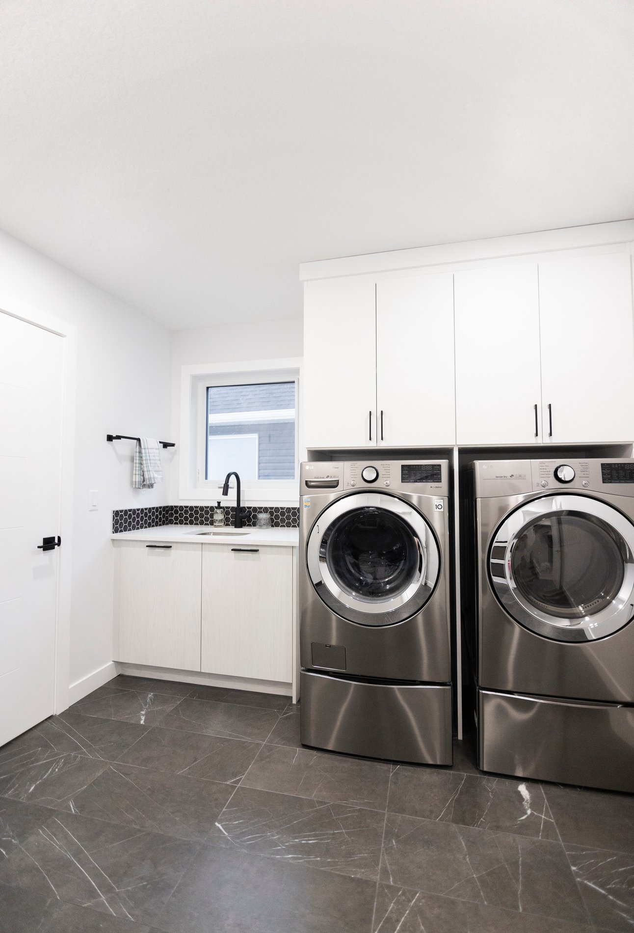 White walk-in laundry room Simple white laundry room. Upper cabinets over the washer and dryer with lower cabinets to the side.