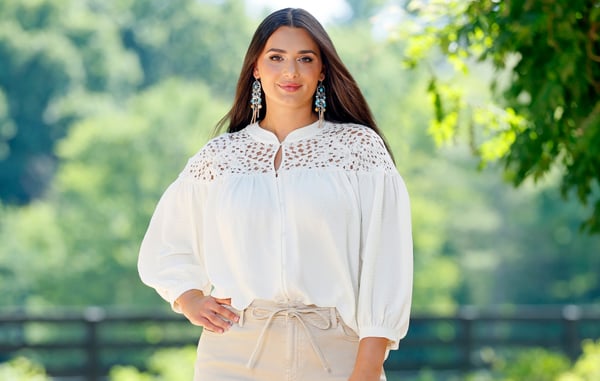 Woman is wearing a plus size white long sleeve blouse from Cato Fashions.