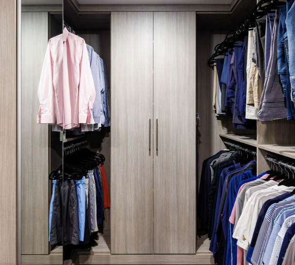 Light Gray Men's Closet Img 7 California Closets Westchester County NY Gray Walk-in Closet Full Room Dressing Room with Double Hanging Dedicated Shoe Wall with Lighting and a Center Island with Black Leather Jewelry Drawers