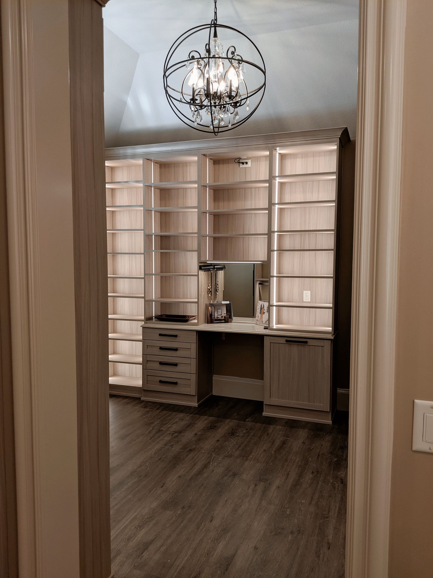 Chic Walk-In Closet with Chandelier and Lighting Luxurious walk-in closet with a chandelier and built-in vanity.
