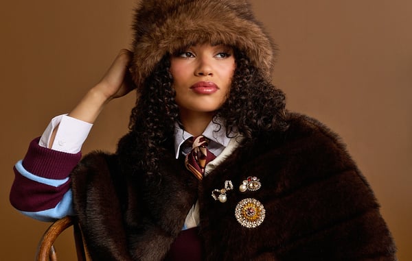 Woman is wearing brooches on her sweater, and a brown fur hat.