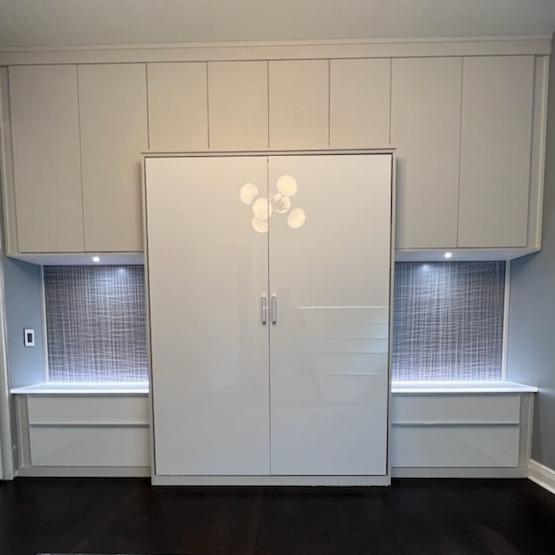 A Multi-Functional Space with Refined Style Custom wall bed and built-in dressers in Linen finish with matte aluminum and polished chrome hardware, high-gloss white acrylic drawer faces, ¼” struck Pure Ecoresin back panels, backlit Chroma Resin countertops in White Out, recessed matte aluminum puck lighting, and a queen wall bed with matching acrylic door face.