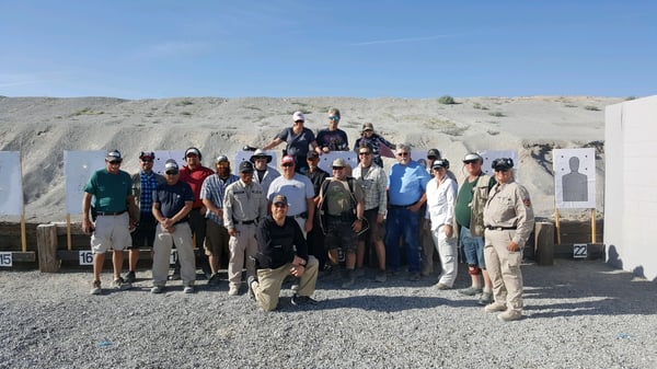 Photo of group of people in front of a mountain at a shooting range